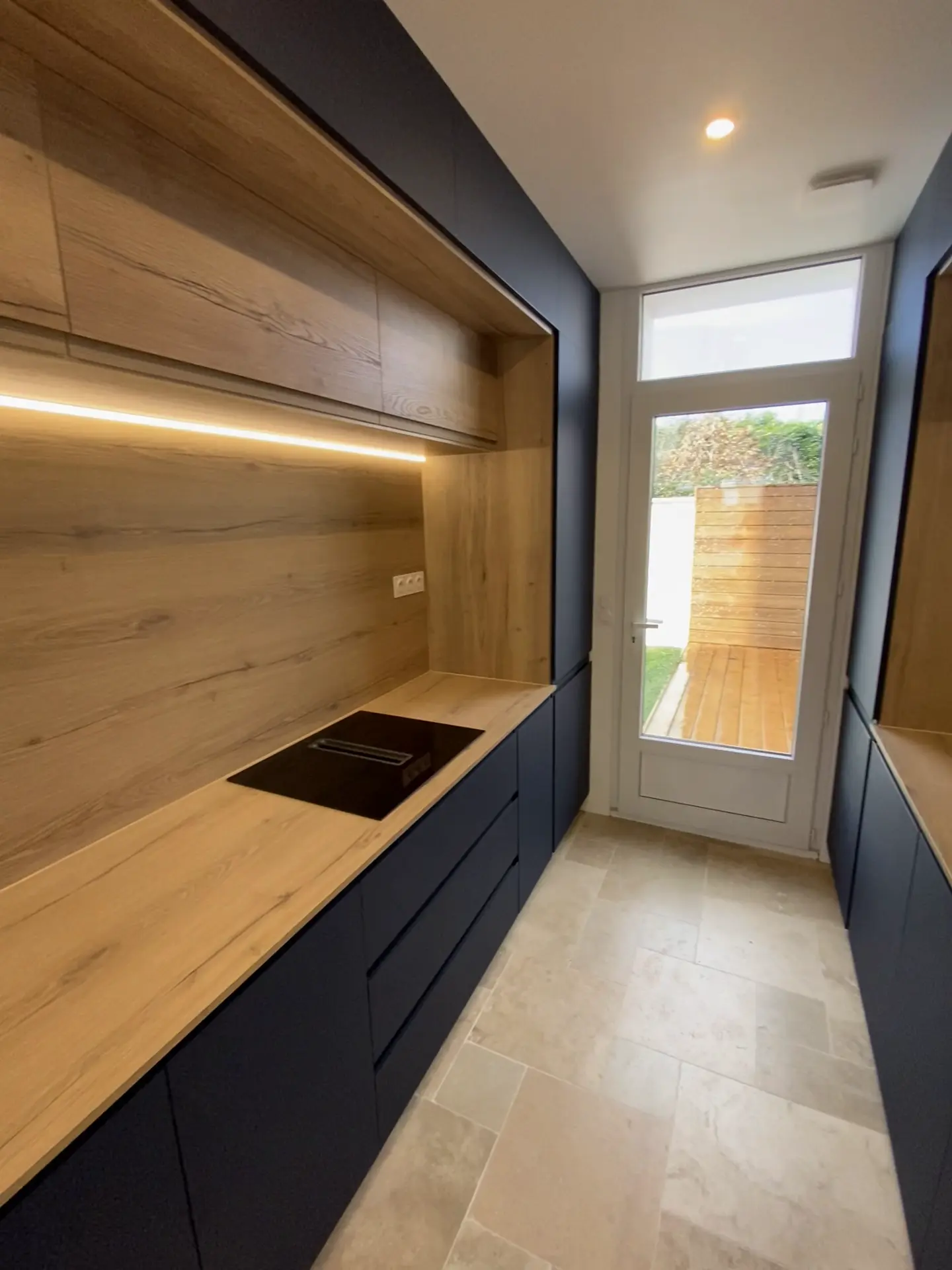 Cuisine aux façades bleu nuit, niches et plan de travail aspect bois