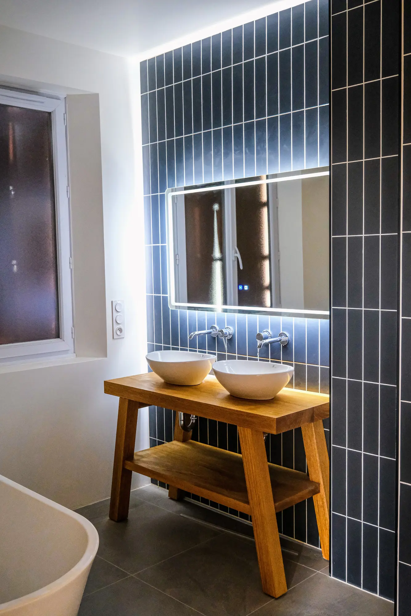 Meuble double vasque en bois devant un revêtement bleu profond